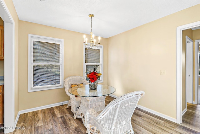 dining space featuring an inviting chandelier, baseboards, and wood finished floors