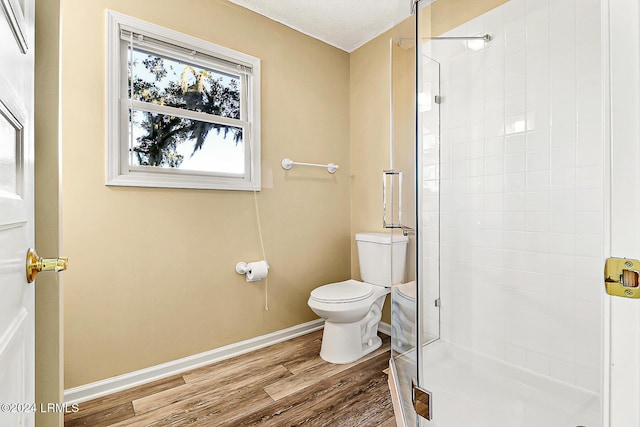 full bath featuring baseboards, a shower stall, toilet, and wood finished floors