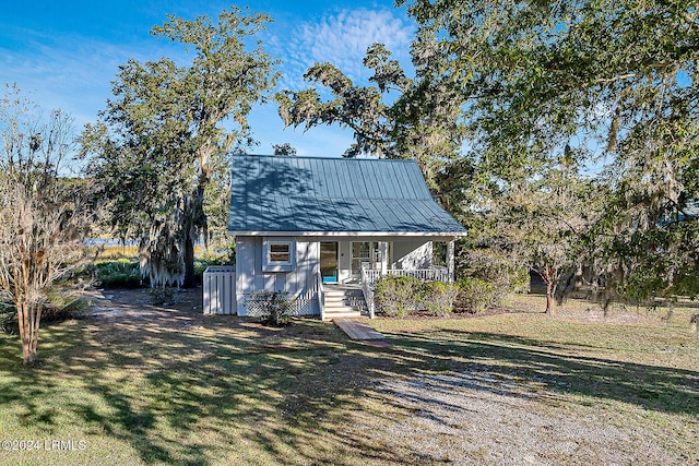 view of front of property with a porch, metal roof, and a front lawn