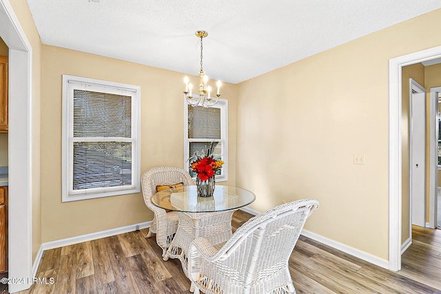 dining area featuring a notable chandelier, baseboards, and wood finished floors