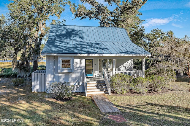 view of front of house with metal roof, a standing seam roof, a porch, and a front yard