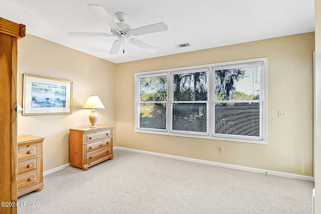 bedroom featuring visible vents, baseboards, a ceiling fan, light colored carpet, and a textured ceiling