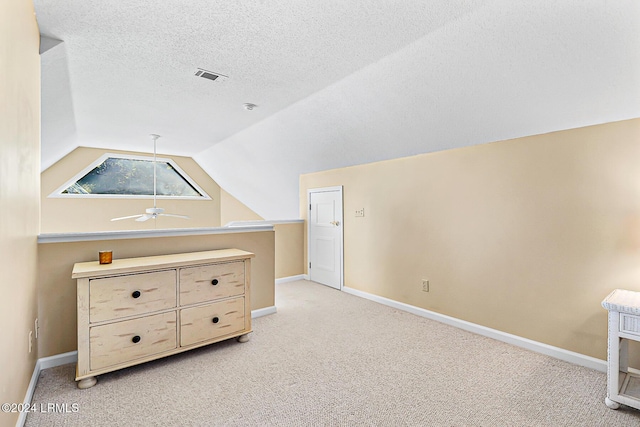 additional living space with lofted ceiling, light colored carpet, visible vents, a textured ceiling, and baseboards