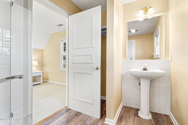 bathroom featuring wood finished floors, visible vents, and tile walls