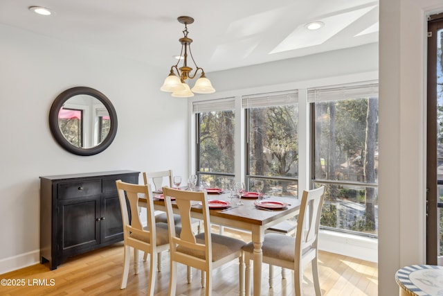 dining area with an inviting chandelier, a skylight, and light hardwood / wood-style floors