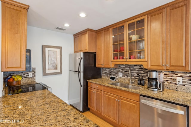 kitchen featuring stainless steel appliances, tasteful backsplash, light stone countertops, and sink