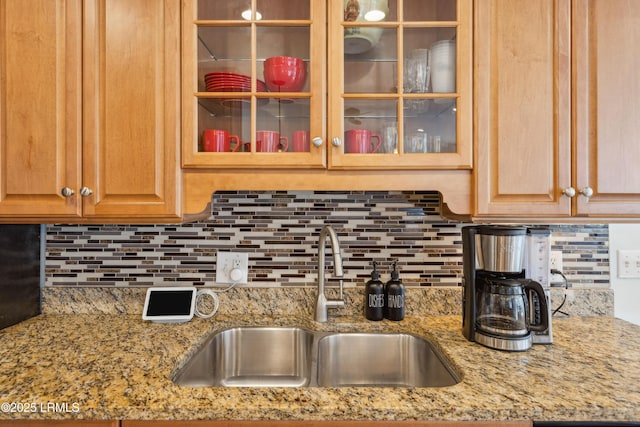 kitchen with sink, light stone counters, and decorative backsplash