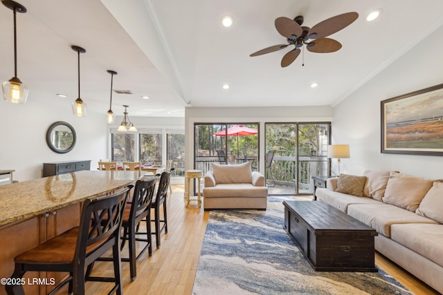 living room with ceiling fan, ornamental molding, and light hardwood / wood-style floors