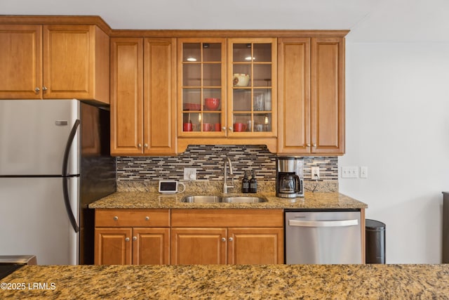 kitchen featuring light stone counters, stainless steel appliances, sink, and decorative backsplash