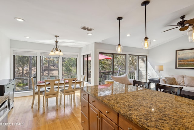 kitchen with stone counters, vaulted ceiling, pendant lighting, and light wood-type flooring