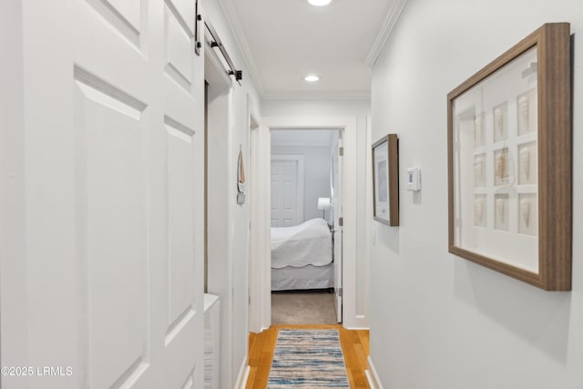 hall featuring hardwood / wood-style flooring, ornamental molding, and a barn door