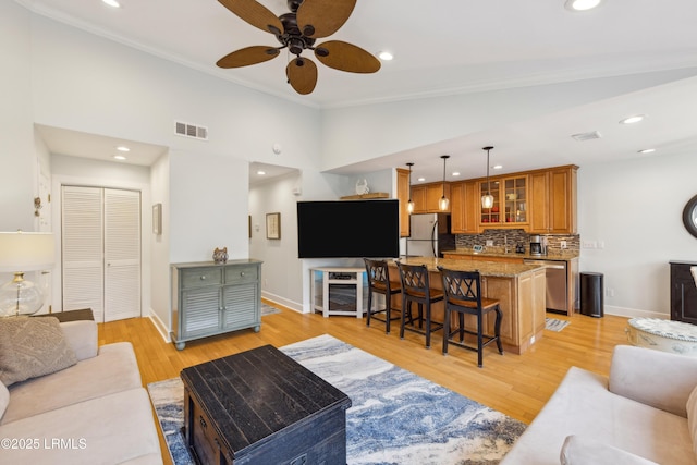 living room featuring ceiling fan, high vaulted ceiling, ornamental molding, and light hardwood / wood-style floors