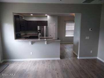 kitchen with baseboards, a breakfast bar, wood finished floors, a peninsula, and stainless steel refrigerator with ice dispenser