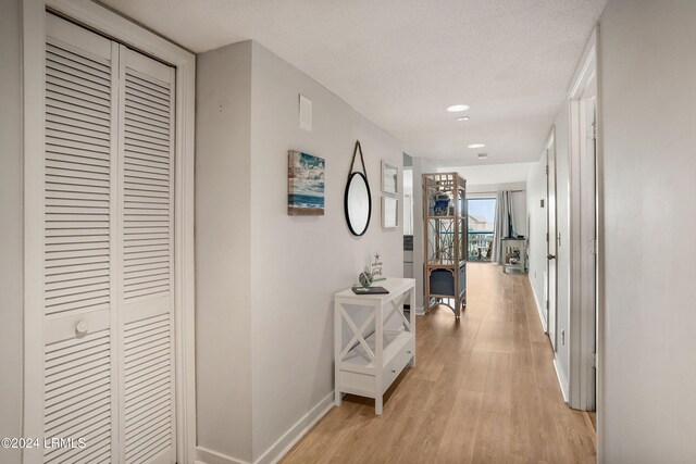 hall with a textured ceiling and light wood-type flooring