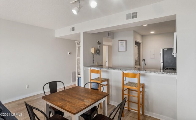 dining area with sink, track lighting, and light wood-type flooring