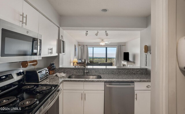 kitchen featuring ceiling fan, stainless steel appliances, sink, and white cabinets