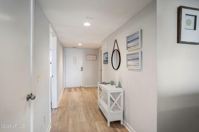 hall featuring light hardwood / wood-style floors and a textured ceiling