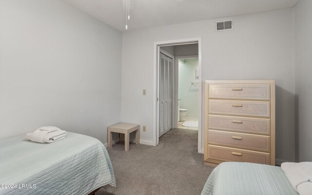 carpeted bedroom featuring ensuite bathroom and a textured ceiling