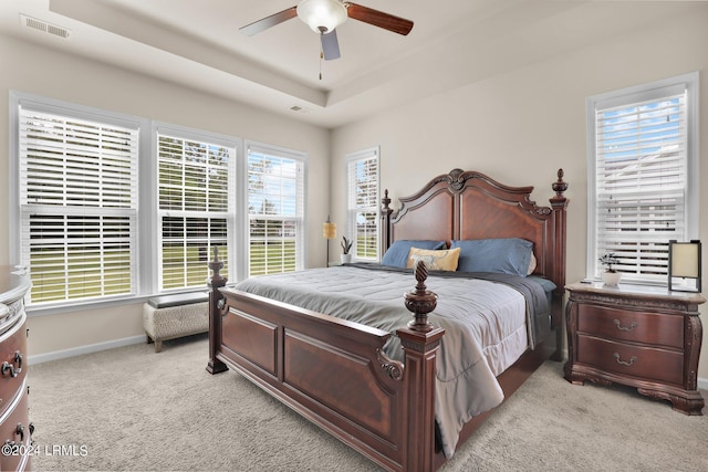 carpeted bedroom featuring a raised ceiling and ceiling fan