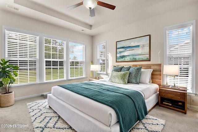 bedroom featuring ceiling fan, a raised ceiling, and light carpet