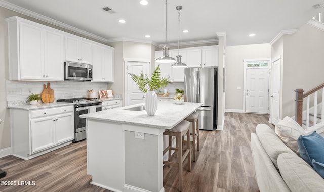 28 Laughing Gull Dr, Beaufort, SC 29907 - kitchen featuring appliances with stainless steel finishes, wood finished floors, a kitchen breakfast bar, decorative backsplash, and ornamental molding