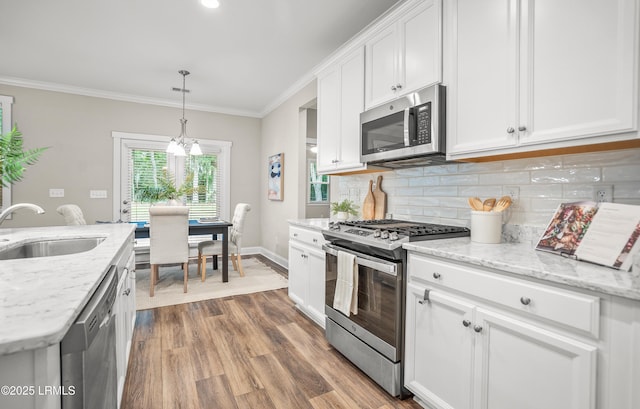 28 Laughing Gull Dr, Beaufort, SC 29907 - kitchen with appliances with stainless steel finishes, a sink, ornamental molding, white cabinetry, and decorative backsplash