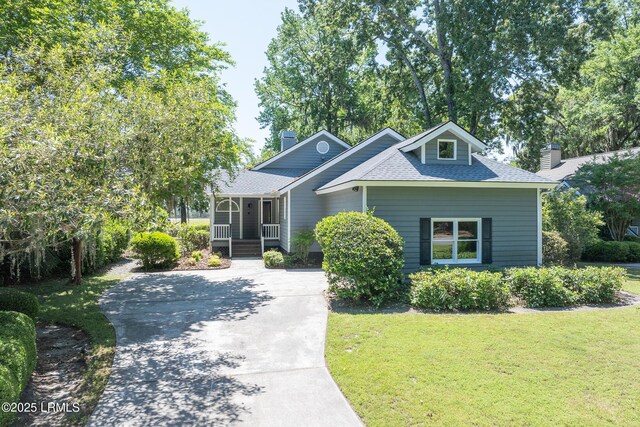 6 River Marsh Ln, Okatie, SC 29909 - view of front of property featuring covered porch, a front yard, roof with shingles, a chimney, and concrete driveway