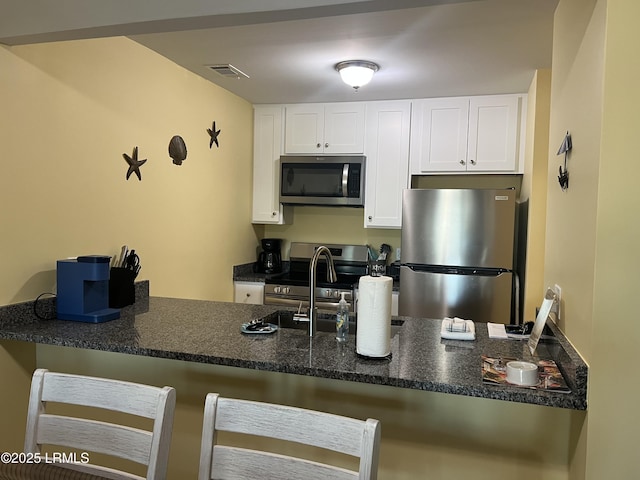 kitchen with sink, kitchen peninsula, white cabinets, and appliances with stainless steel finishes