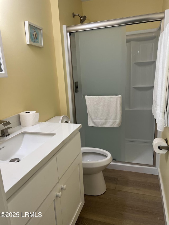 bathroom featuring vanity, toilet, hardwood / wood-style floors, and a shower with shower door