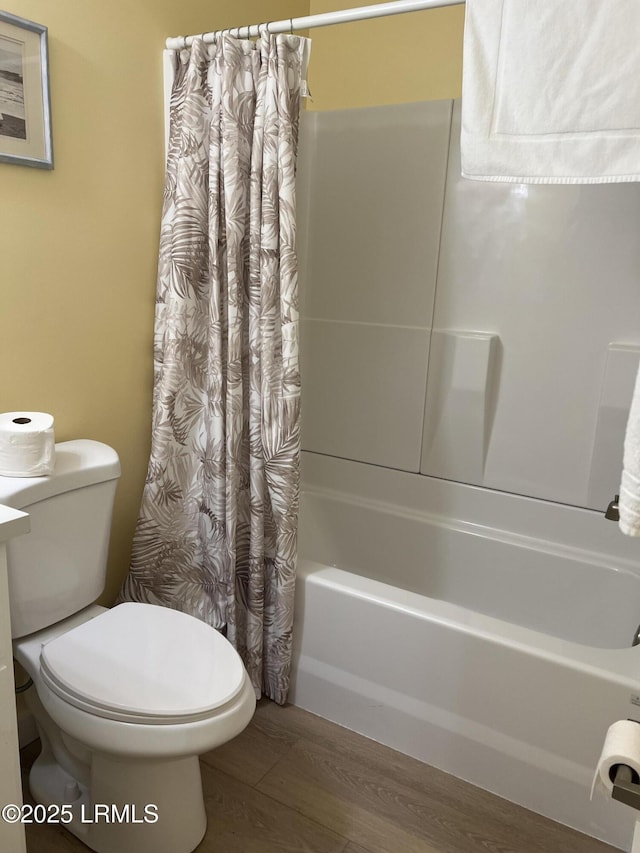 bathroom with wood-type flooring, shower / tub combo, and toilet