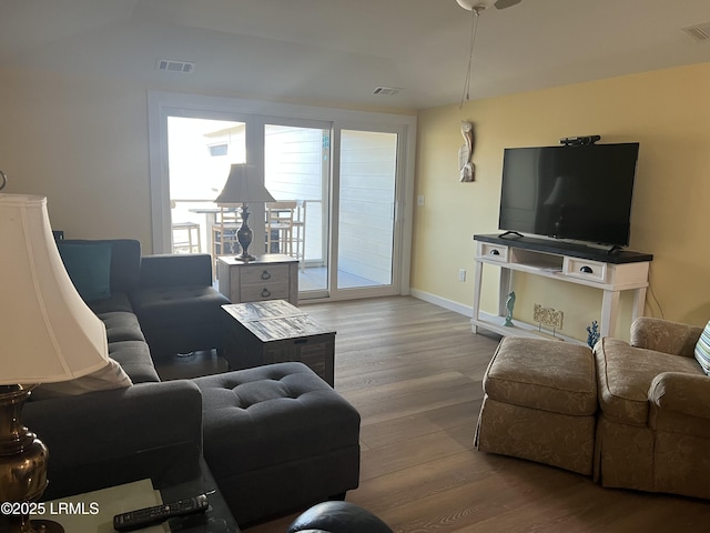 living area with baseboards, visible vents, and wood finished floors