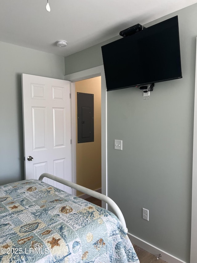 bedroom with electric panel, dark wood-style flooring, and baseboards