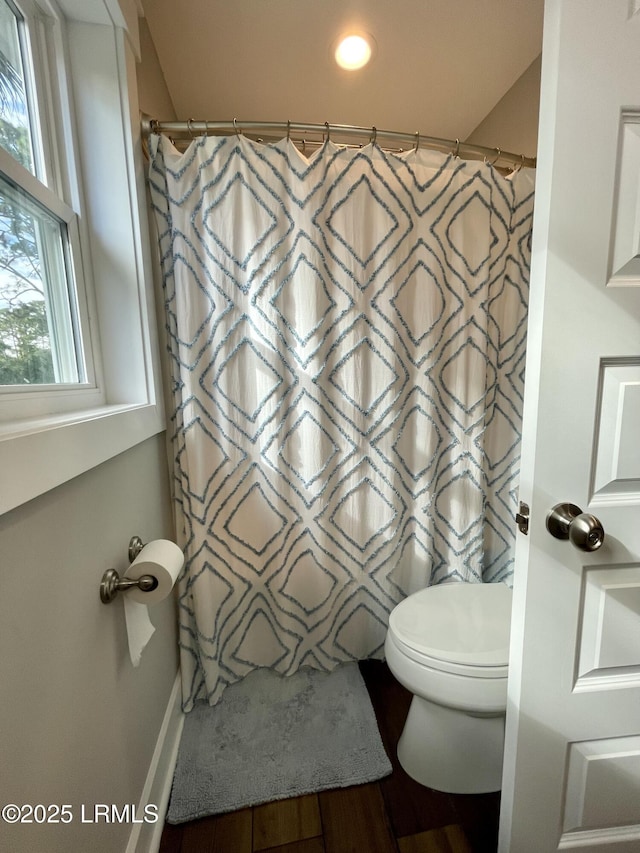 bathroom with a shower with shower curtain and toilet