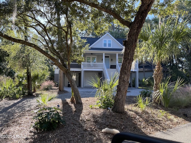 coastal inspired home featuring a porch, stairway, and a garage