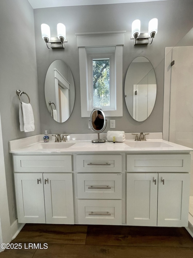 full bathroom with double vanity, a sink, and wood finished floors