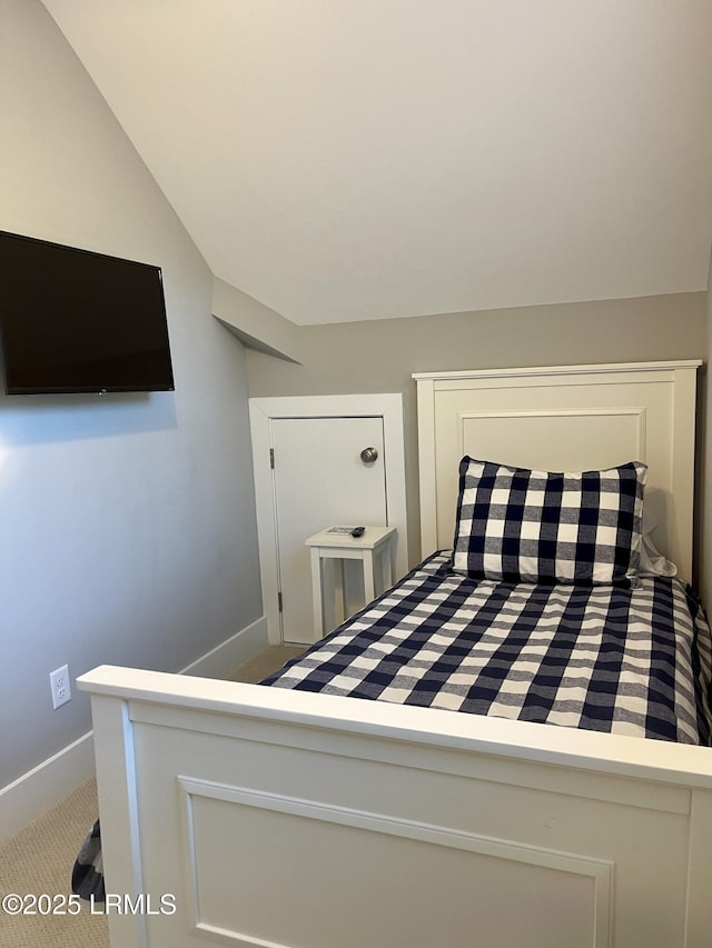 bedroom with lofted ceiling, light carpet, and baseboards