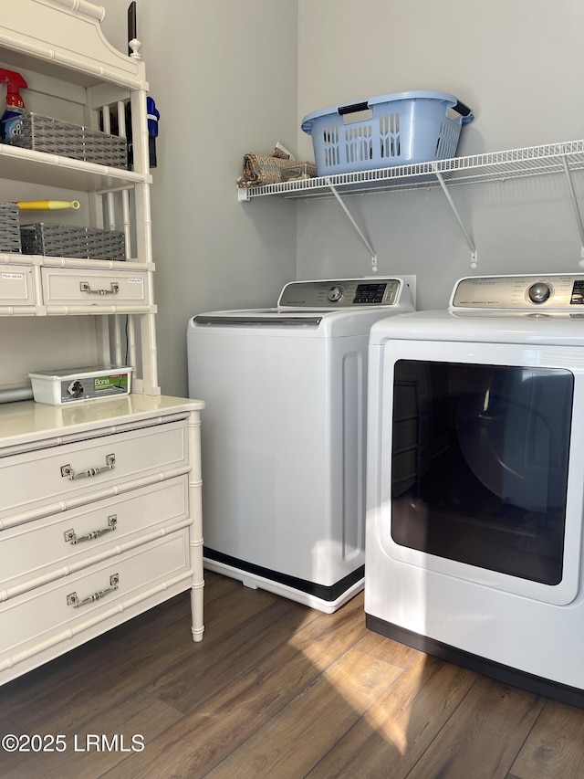 washroom with laundry area, washing machine and dryer, and dark wood finished floors