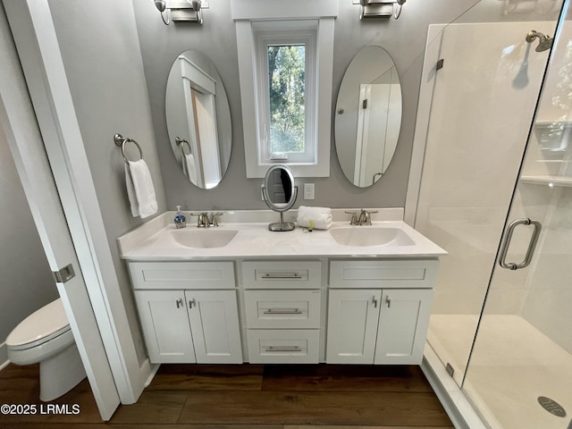 bathroom featuring toilet, a shower stall, a sink, and wood finished floors