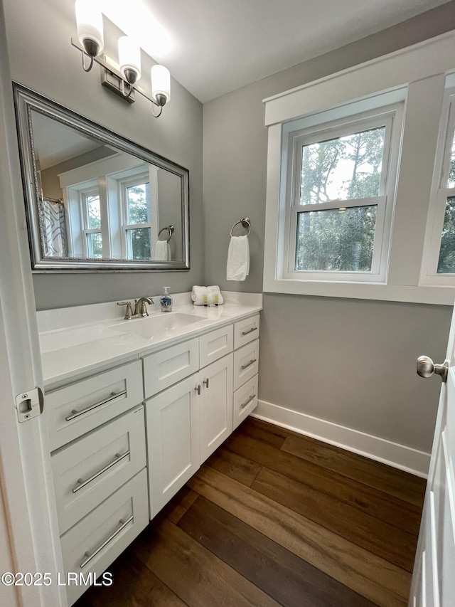 bathroom featuring a wealth of natural light, vanity, baseboards, and wood finished floors