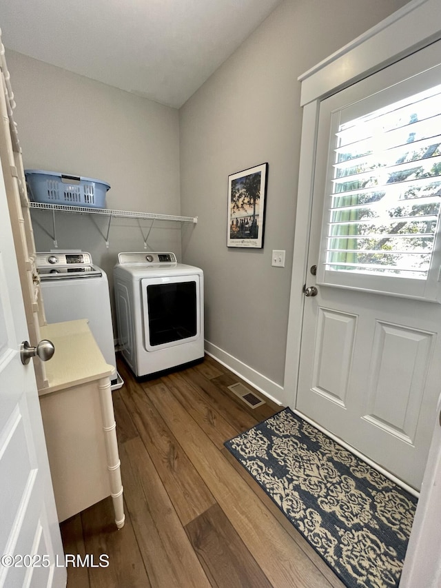 clothes washing area with laundry area, baseboards, visible vents, dark wood-type flooring, and separate washer and dryer