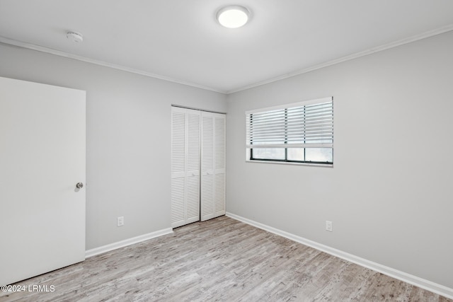 unfurnished bedroom featuring light hardwood / wood-style flooring, ornamental molding, and a closet