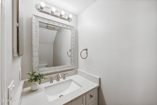 bathroom featuring vanity, toilet, and a textured ceiling