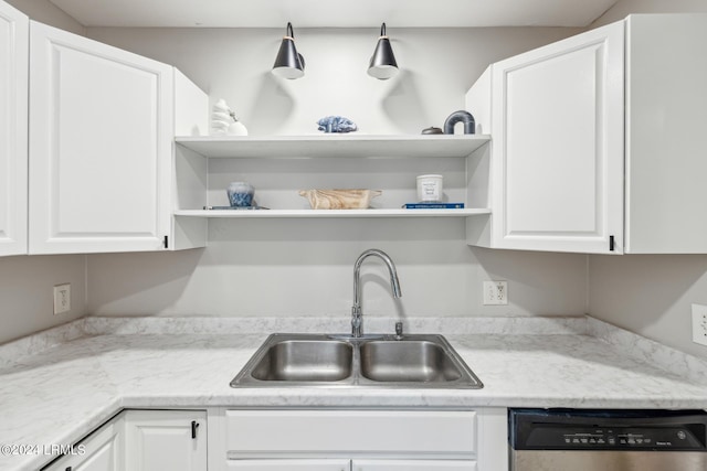 kitchen with white cabinetry, sink, stainless steel dishwasher, and light stone countertops