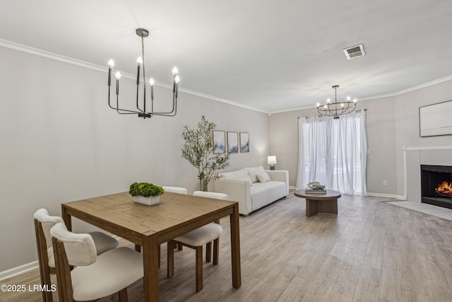 dining area with a tile fireplace, ornamental molding, and a chandelier