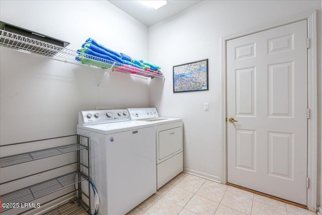 laundry room with laundry area, light tile patterned flooring, washing machine and clothes dryer, and baseboards