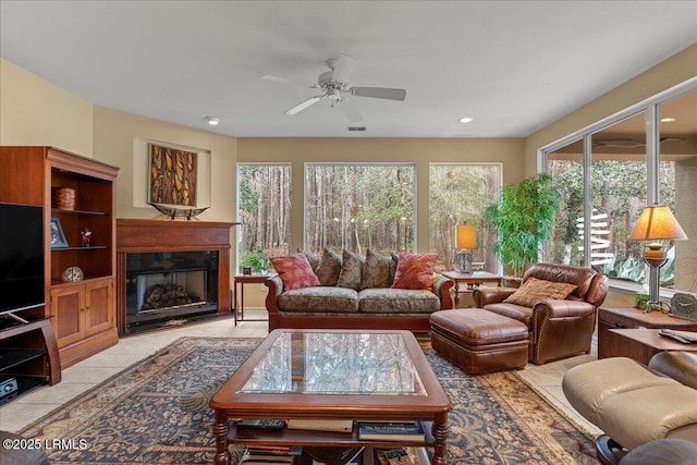 living room featuring light tile patterned floors, ceiling fan, recessed lighting, visible vents, and a glass covered fireplace