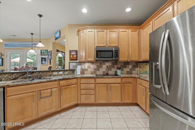 kitchen with light tile patterned floors, stainless steel appliances, a sink, dark stone countertops, and pendant lighting