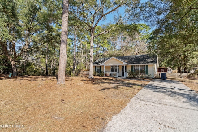 view of front facade with covered porch, aphalt driveway, and fence