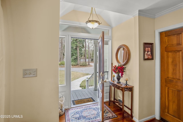 entrance foyer featuring vaulted ceiling, dark wood-style floors, ornamental molding, and a healthy amount of sunlight