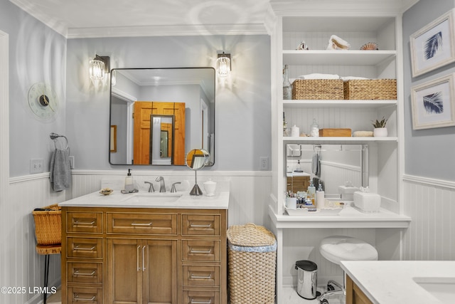 bathroom with a wainscoted wall, vanity, crown molding, and built in features